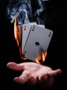 A fanned out spread of ace cards on fire hovering over an upturned hand